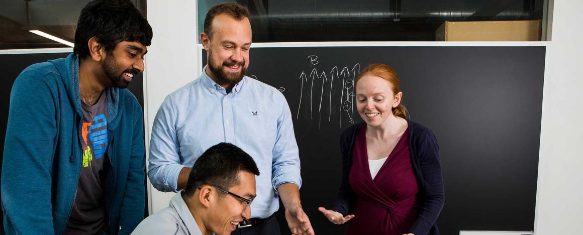 Professor and students looking at the computer together